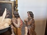 a statue of a man and a woman sitting on a table next to a bowl of bread
