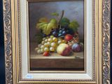 un tableau représentant des raisins et des pommes posés sur une table, avec un chevalet en bois