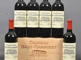 six bottles of red wine in a wooden crate on a table