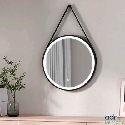 un miroir rond accroché au mur au-dessus d'une commode