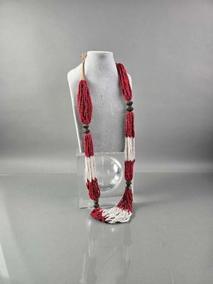 collier de perles rouges et blanches sur un mannequin tenant une boule de verre