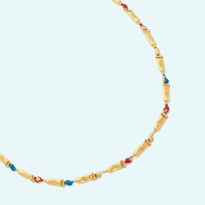 a gold necklace with turquoise and red beads on a white background