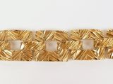 gros plan d'un bracelet en or sur une surface blanche