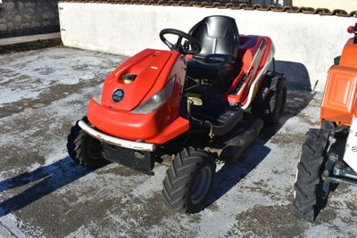a small red tractor parked next to a smaller orange tractor