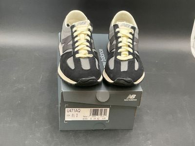 pair of black and white sneakers with yellow laces on top of a box