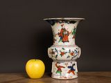 a white vase sitting next to an apple on a table