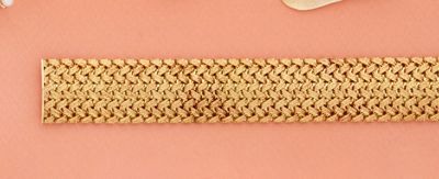 un bracelet au crochet et une paire de ciseaux posés sur un fond rose