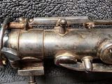 a silver saxophone that is laying on a black cloth