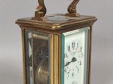 une petite horloge en laiton surmontée d'un oiseau