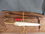 four umbrellas and two canes in a brown bag