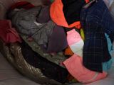 a pile of clothes that is sitting on a bed