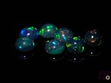 quelques perles d'oplite vertes et bleues sont disposées sur un fond noir