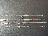 quatre bracelets en argent ornés de breloques différentes, posés sur un fond noir