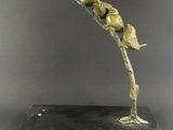 une sculpture en bronze représentant un oiseau perché sur une branche d'arbre