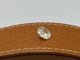 a close up of a diamond sitting on top of a brown leather belt