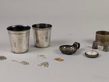 une coupe en argent et d'autres objets en argent posés sur une surface blanche