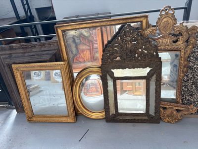 beaucoup de cadres et de miroirs anciens posés sur la table