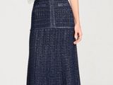 La femme porte une robe bleue et des sandales, et tient un sac à main.