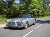 a silver car driving down the road with trees in the background