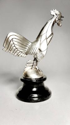 an image of a silver rooster statue on a black pedestal