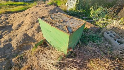 a green box sitting in the middle of a pile of dirt