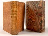 an old book sitting on top of a wooden block next to a smaller book