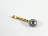 a close up of a black pearl on a gold pin