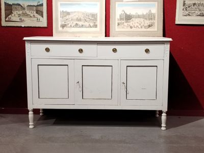 a white cabinet with two pictures on the wall behind it