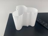 un vase blanc avec une télécommande posé sur une table noire
