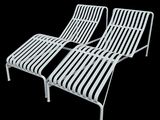 pair of white metal lounge chairs on a black background