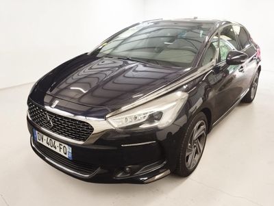 Une voiture noire est garée dans une pièce blanche au sol blanc.