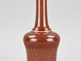 an orange vase sitting on top of a white table next to a white wall