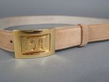 ceinture en cuir beige avec une boucle dorée sur un fond gris