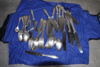 de nombreuses cuillères et fourchettes en argent posées sur une nappe bleue