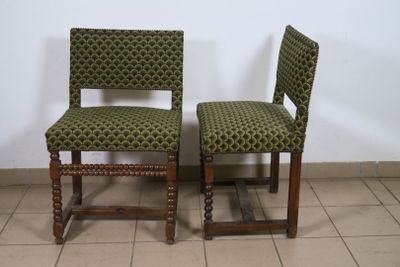 pair of green upholstered chairs on tiled floor with white wall