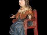 a statue of a woman sitting on a red chair