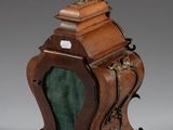 an antique wooden clock with a green glass in the middle of it
