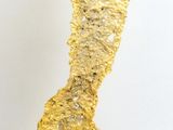 sculpture en feuille d'or posée sur un socle, sur une surface blanche, avec un fond blanc