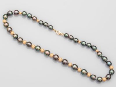 a black pearl and gold necklace on a white background