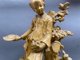 a statue of a boy with a bird on a tree stump