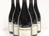 six bottles of red wine are lined up on a white surface