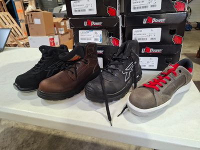 several pairs of shoes are on a table with boxes of boxes in the background