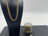 a black mannequin with a gold necklace, bracelet and bracelet
