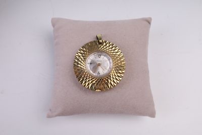 une horloge dorée et blanche posée sur un coussin, sur une surface blanche