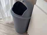a trash can next to a cabinet in a bathroom