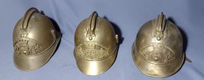 three antique brass fire helmets on a blue background