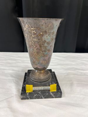 a silver vase sitting on a marble base on a table