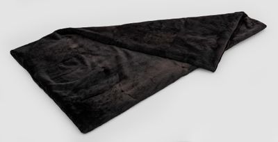 La couverture noire est posée sur une surface blanche, à côté d'une paire de ciseaux.