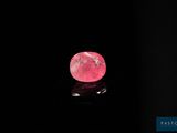 un diamant rose sur une surface noire, dans l'obscurité