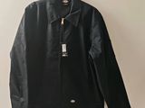 une veste en cuir noir suspendue à un cintre accroché au mur